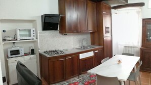 A compact kitchen with wooden cabinets, a microwave, a gas stove, and a sink. - Beautiful apartment for 4 guests with WIFI, TV and pets allowed (Orta San Giulio)