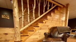 A wooden staircase with a leather chair in a room with wooden flooring. - ADK Lake House Vacation, Cozy 5 Bedroom & 2 Bath (Old Forge)