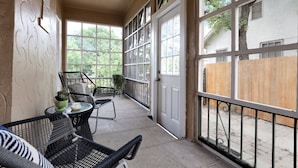 A covered patio area with wicker chairs, a small table, and a potted plant.