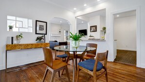 A dining area with a round glass table, wooden chairs, and a potted plant.