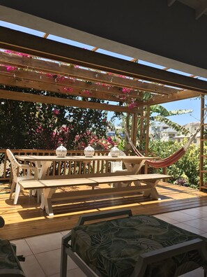 Relax in a serene outdoor oasis with a hammock, wooden bench, and lush greenery.