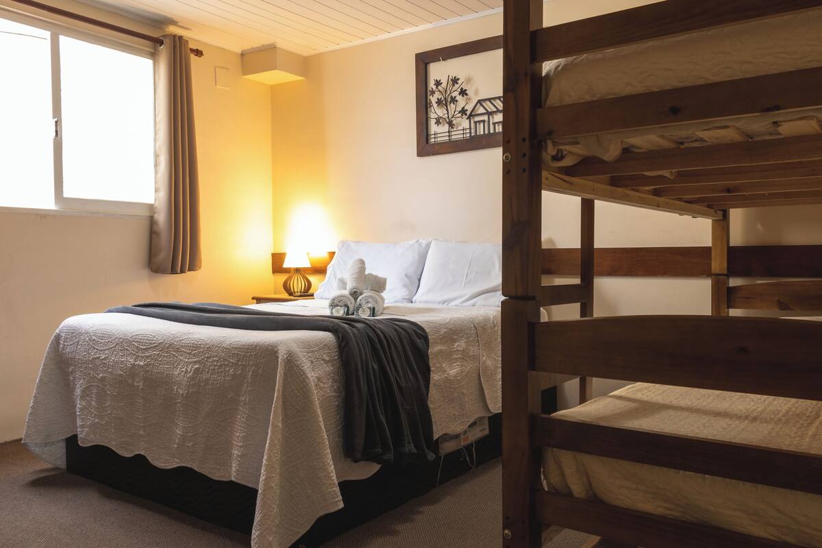 Une chambre avec un lit superposé, une table de chevet avec une lampe et un tableau encadré au mur.