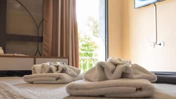 Una habitación de hotel con una cama, un televisor en la pared y una ventana con cortinas.