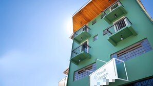 A multi-story building with balconies and a sign indicating it is a hotel.