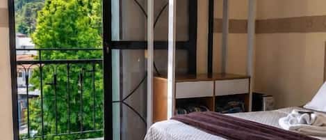 Un dormitorio con cama, ventana y balcón.