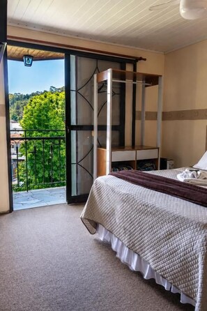 Un dormitorio con cama, ventana y balcón.