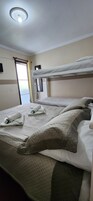 Una habitación de hotel con una litera, una cama individual y una lámpara en el techo.