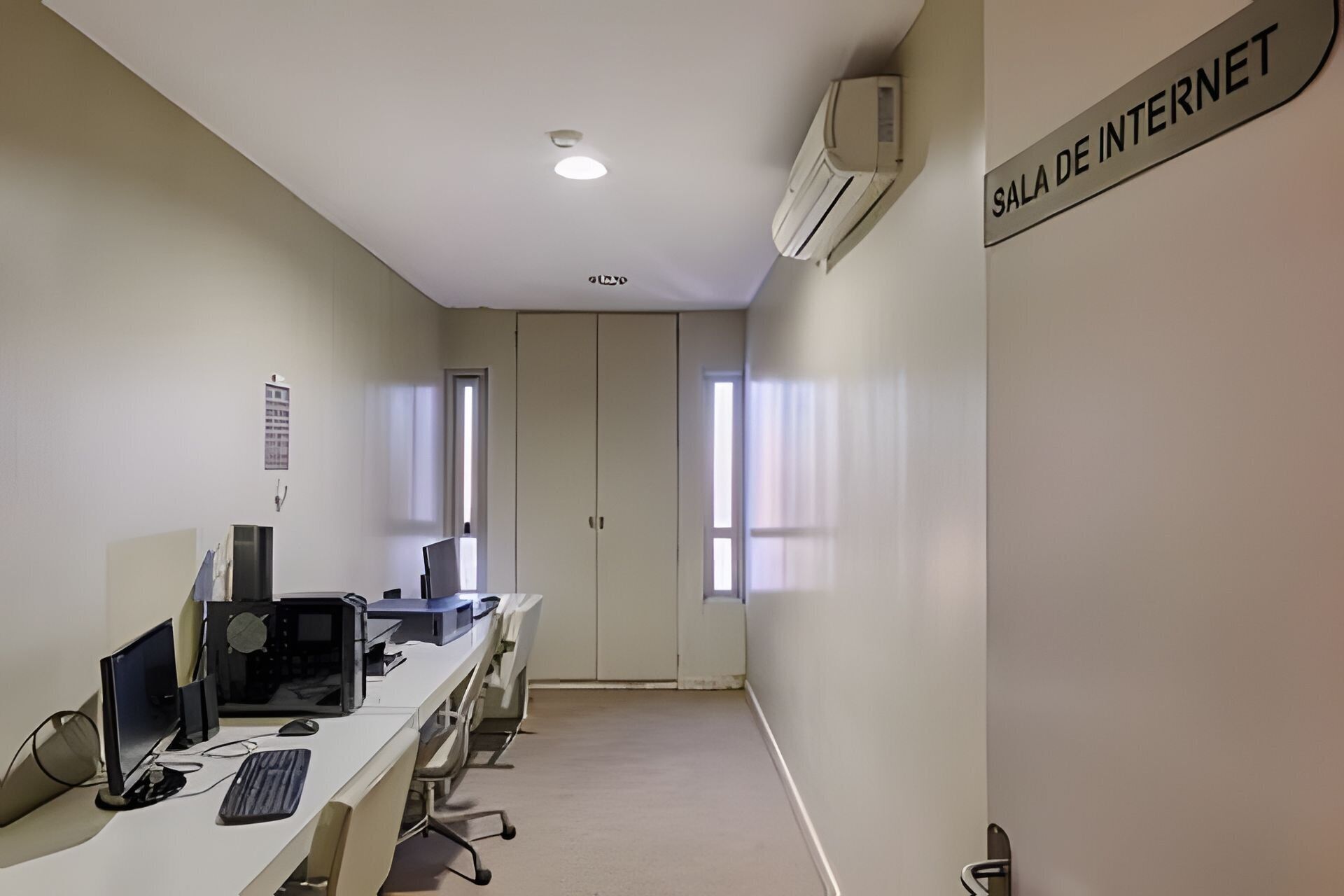A conference room with a long table, multiple computer monitors, and a sign reading "Sala de Internet".