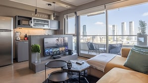 Un salon moderne doté d’un téléviseur à écran plat, d’un canapé et d’un balcon offrant une vue sur la ville.