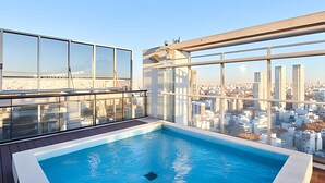 Une piscine sur le toit offrant une vue sur la ville, de grandes baies vitrées et une architecture moderne.
