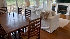 Un salon spacieux avec une table à manger en bois, des canapés blancs et une cheminée.