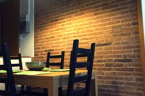 Enjoy meals in this cozy dining area with a rustic brick wall backdrop and a wooden table.