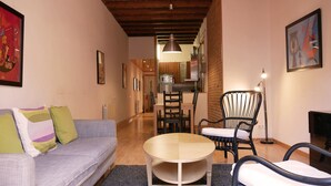 A cozy living room with a sofa, a round coffee table, and a black wicker chair. - Apartment Valencia - Two Bedroom Apartment (Barcelona)