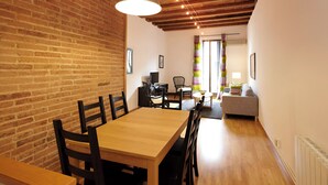 A dining area with a wooden table and chairs, a hanging pendant light, and a brick wall. - Apartment Valencia - Two Bedroom Apartment (Barcelona)