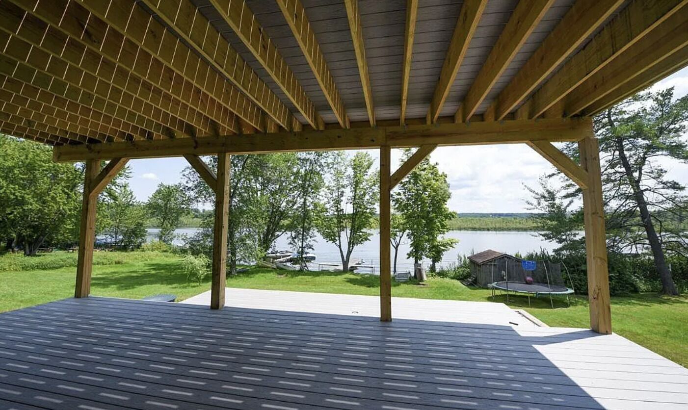 Une terrasse couverte avec vue sur un lac et un petit quai.