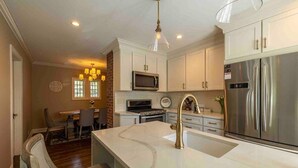 A modern kitchen with white cabinets, stainless steel appliances, and a marble island.