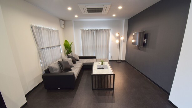 A modern living room with a grey sofa, a coffee table, and a TV mounted on the wall. - OguHouse Beppu (Beppu)