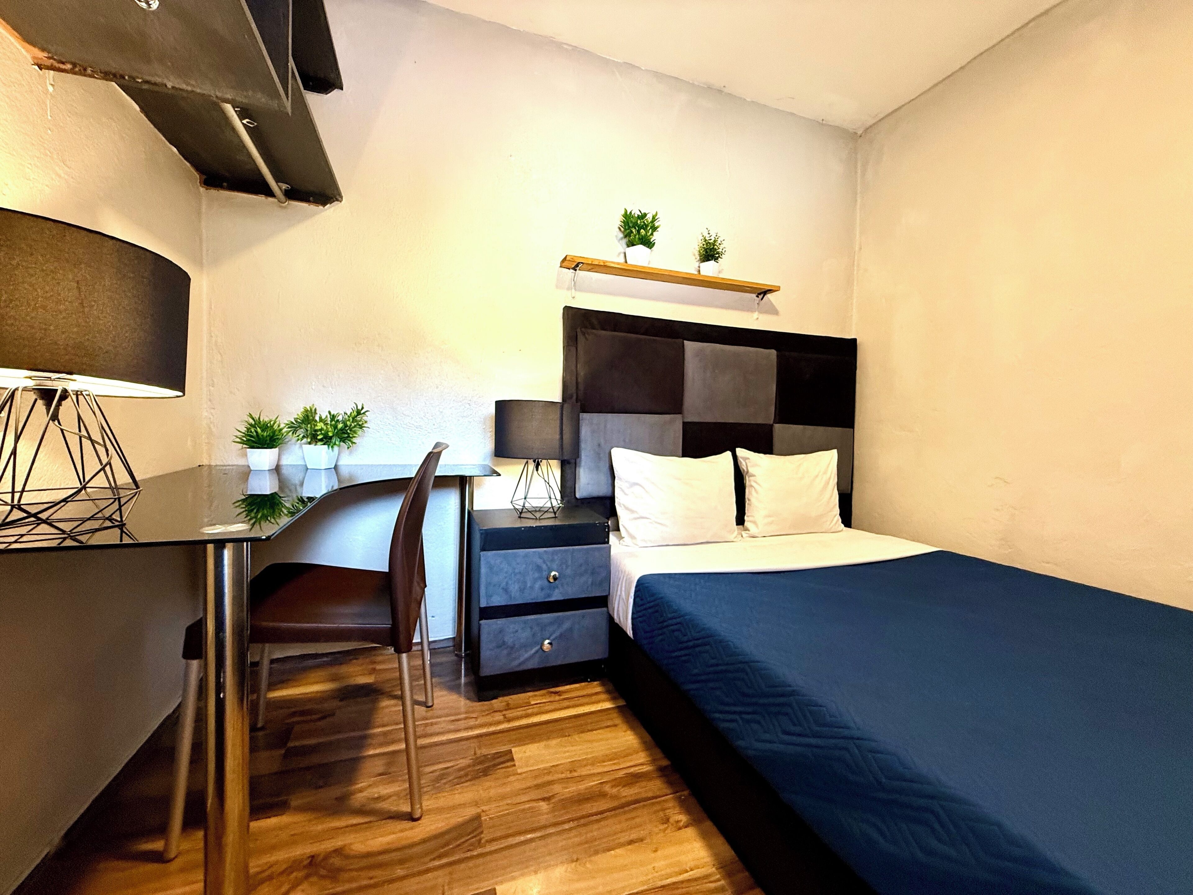 A modern bedroom with a bed, desk, chair, and bedside tables.