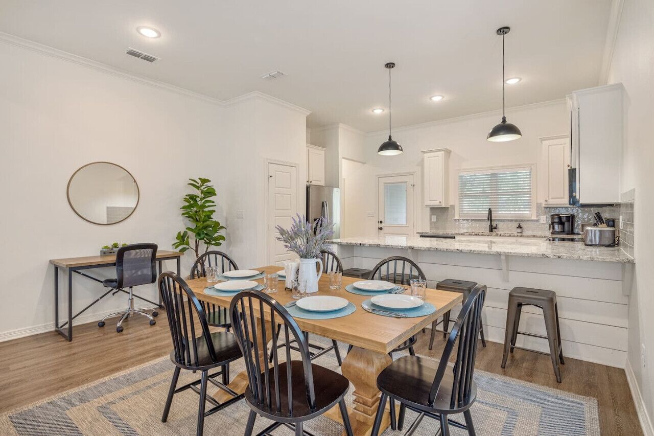 A modern kitchen with white cabinets, a marble countertop, and pendant lighting.