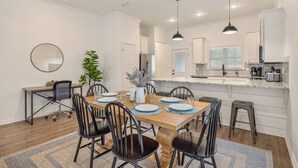 A modern kitchen with white cabinets, a marble countertop, and pendant lighting.