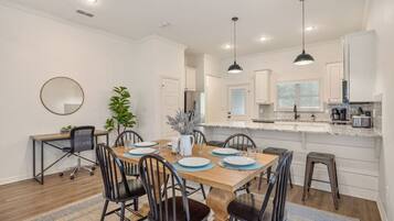 A modern kitchen with white cabinets, a marble countertop, and pendant lighting.