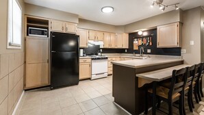 A modern kitchen with a black refrigerator, white stove, and wooden cabinets. - Skyline - Military/Family Friendly (Shiloh)