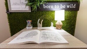 Ein Schreibtisch mit offenem Skizzenbuch, einer Lampe und einem an der Wand befestigten Schild mit der Aufschrift 'born to be wild'.