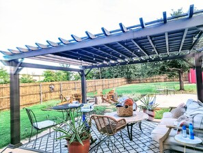 An outdoor patio with a pergola, seating arrangements, and potted plants. - Walk to AT&T Stadium Free Parking Backyard (Arlington)