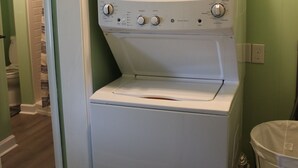 Lavadora de carga frontal y secadora en un cuarto de lavado con paredes verdes.