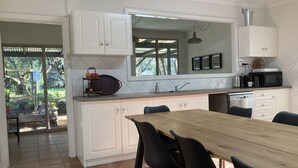 A kitchen with white cabinets, a wooden dining table, black chairs, a sink, and a microwave.