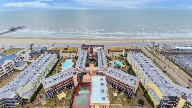 A coastal hotel with multiple buildings, a central courtyard, and a beach view. - HEATED POOL, HOTTUBS, OCEAN/ GULF VIEW! Top Floor, Kitchen, Modern Decor! (Galveston)