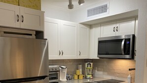 A modern kitchen with white cabinets, stainless steel appliances, and a microwave. - HEATED POOL, HOTTUBS, OCEAN/ GULF VIEW! Top Floor, Kitchen, Modern Decor! (Galveston)