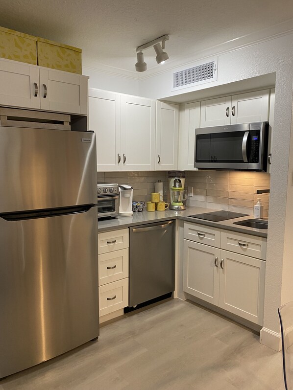 A modern kitchen with stainless steel appliances, white cabinetry, and a microwave.