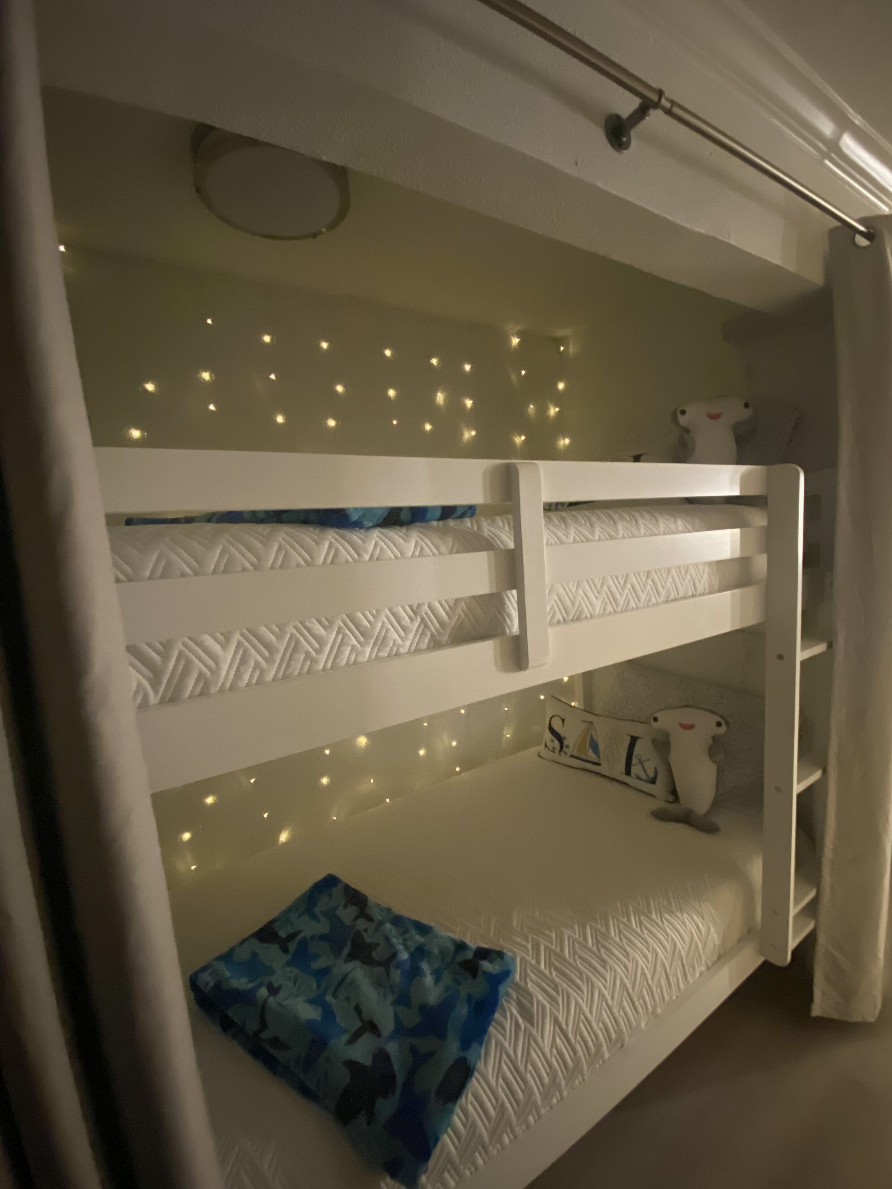 A bunk bed with a decorative ceiling light, a pillow, and a stuffed toy.