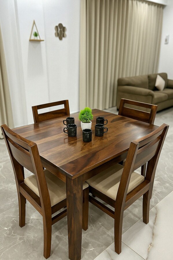 A dining table with four chairs, a potted plant, and four black mugs.