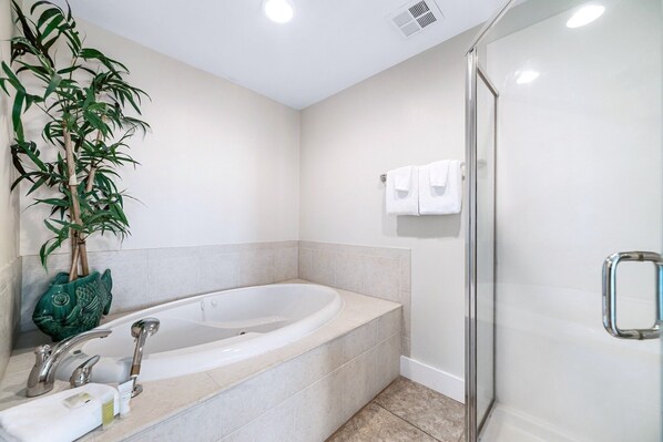 A modern bathroom with a freestanding bathtub, a glass shower enclosure, and a potted plant.