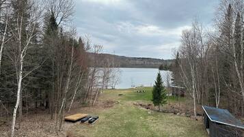 A lakeside property with a wooden deck, a small shed, and a grassy area.