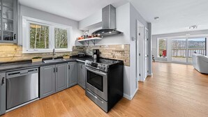Een moderne keuken met grijze kastjes, een zwart fornuis en een groot raam.
