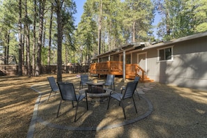 A cabin with a deck, surrounded by tall trees.