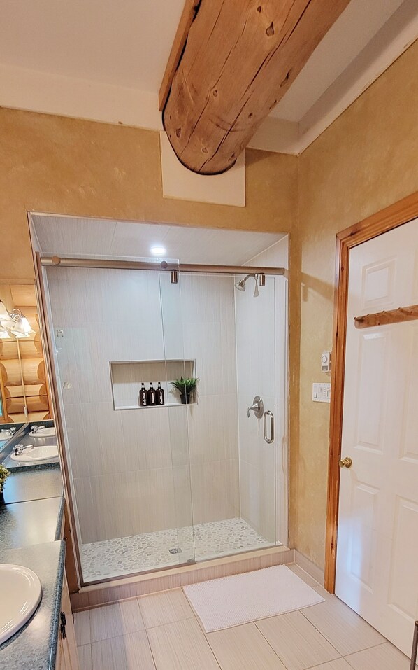 Une salle de bain avec une douche à parois de verre, un lavabo et un miroir.