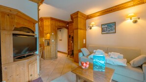 A cozy living room with a wooden entertainment unit, a sofa, and a coffee table with a book and apples. - Mont blanc view with private sauna, Argentière (Chamonix), France (Argentière (Chamonix))