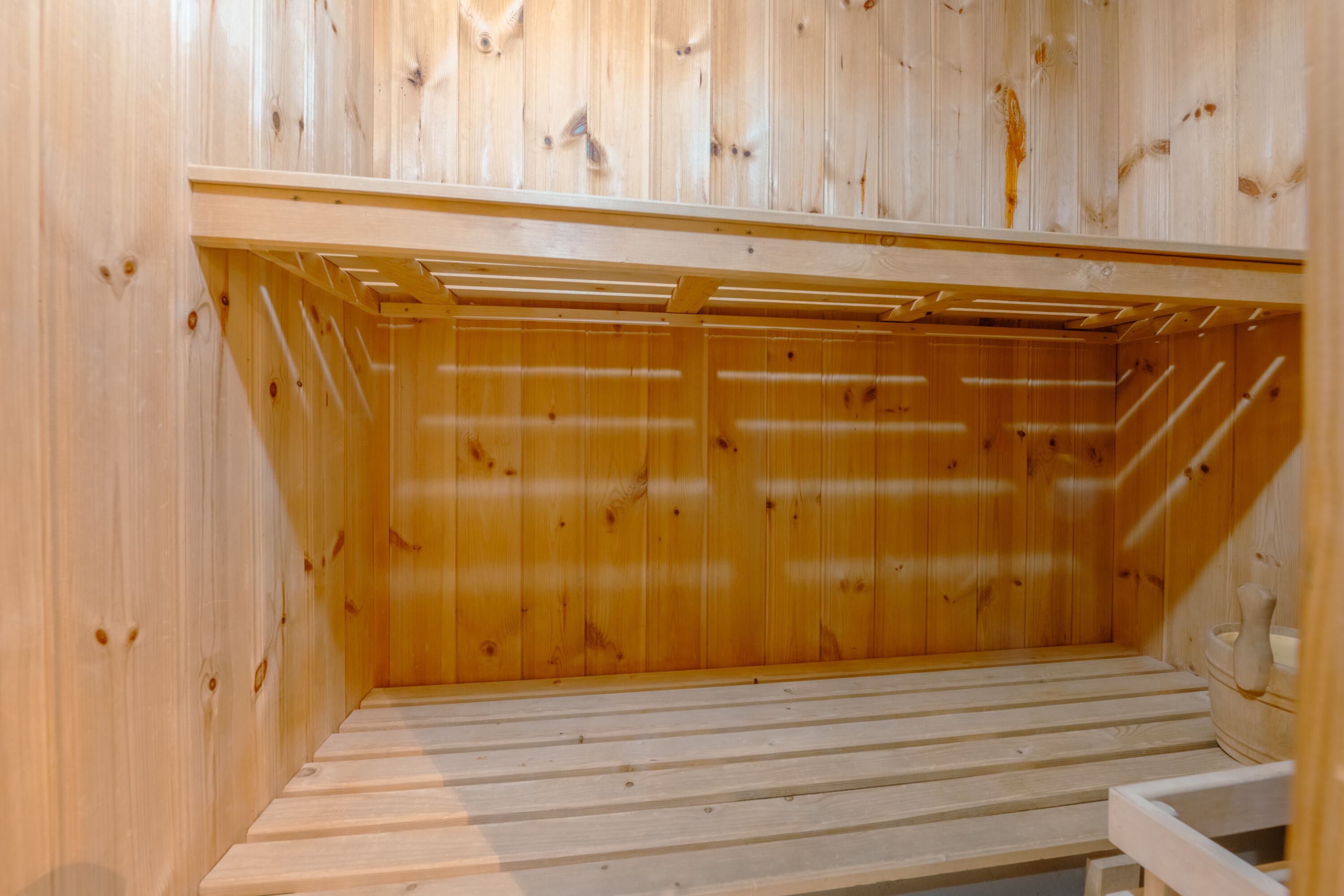 Un sauna en bois avec un banc et un autre banc en bois posé sur le sol.