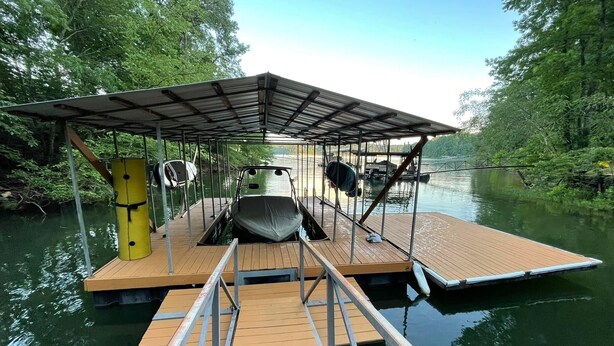 Un muelle flotante con una zona de estar cubierta y un barco.