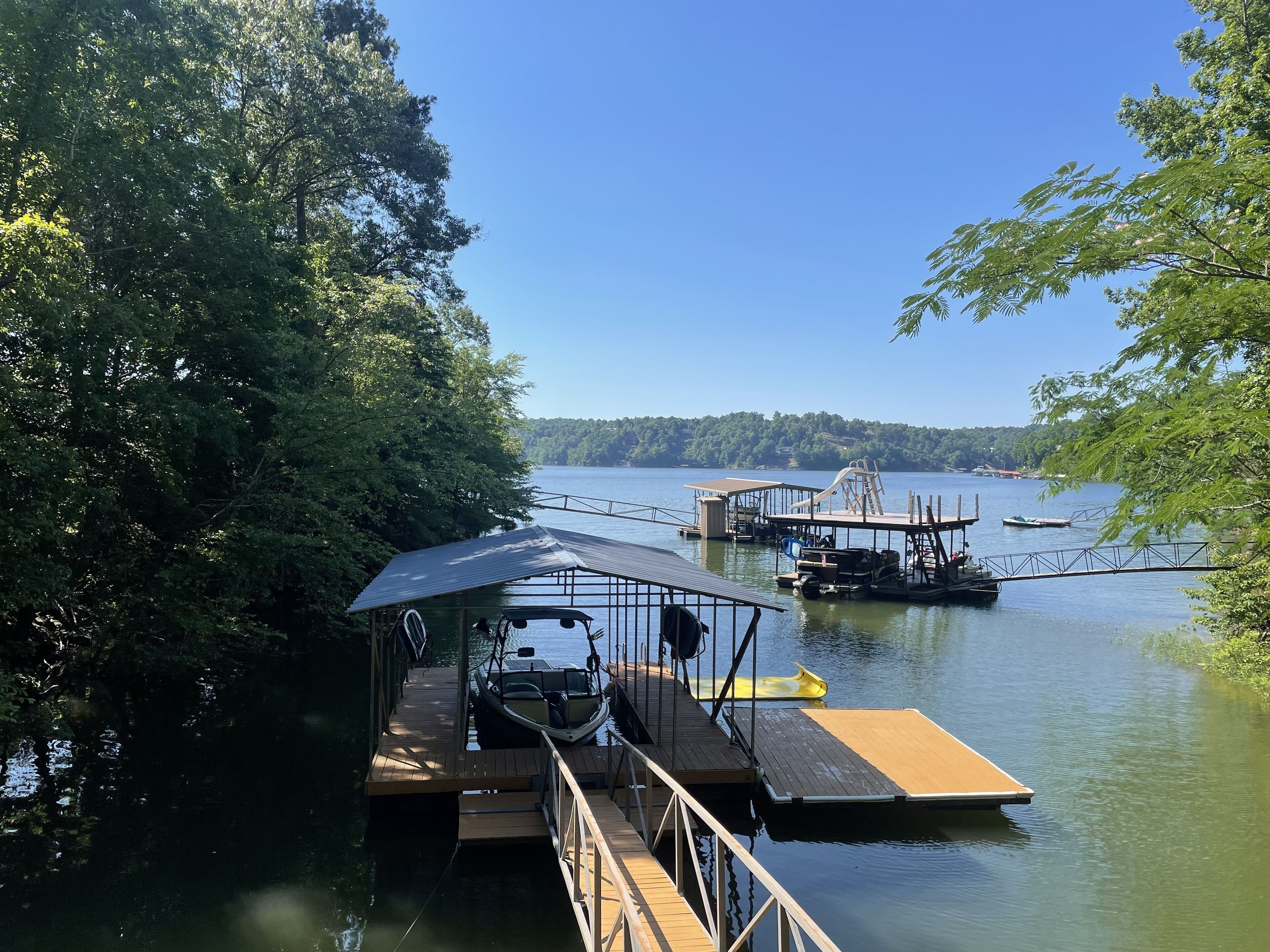 A dock with boats, a covered area, and a forested area.