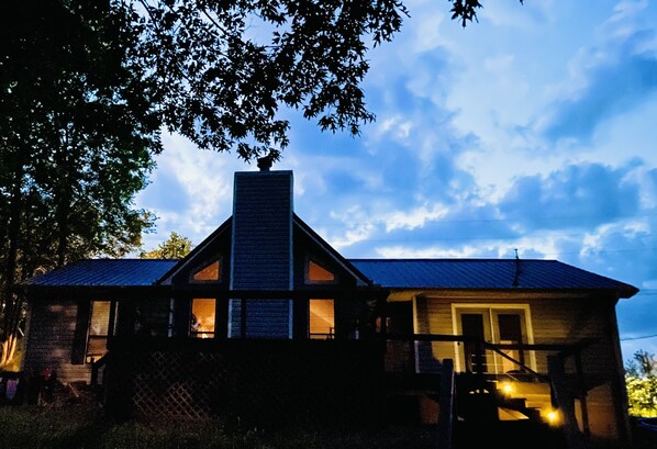 Cozy cabin with a front porch and staircase, set amidst a serene natural setting.