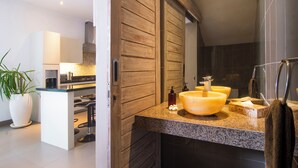 A modern bathroom with a wooden vanity, a large sink, and a mirror.