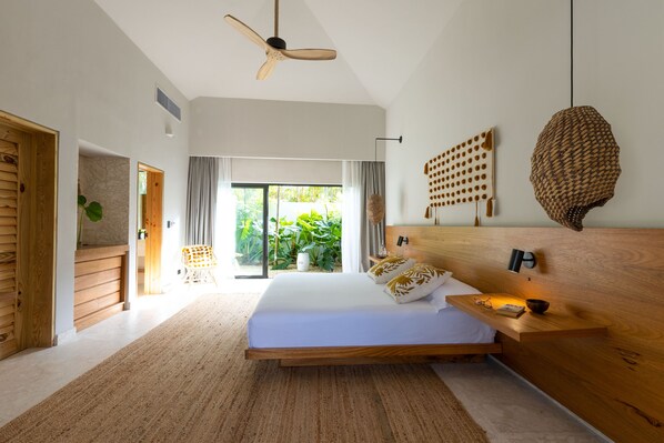 Une chambre moderne avec un grand lit, une tête de lit en bois et une vue sur la verdure.