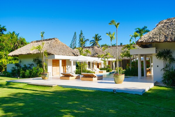Un complexe hôtelier doté de villas aux toits de chaume, d’une piscine et d’une végétation luxuriante.
