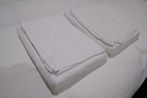 A neatly folded white towel on a bed. - SORARU MIYAKOJIMA (Miyakojima)