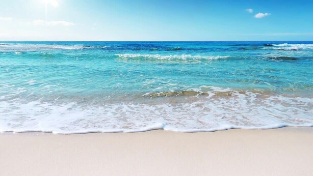 Ein Strand mit klarem, blauem Wasser und sandigem Ufer.